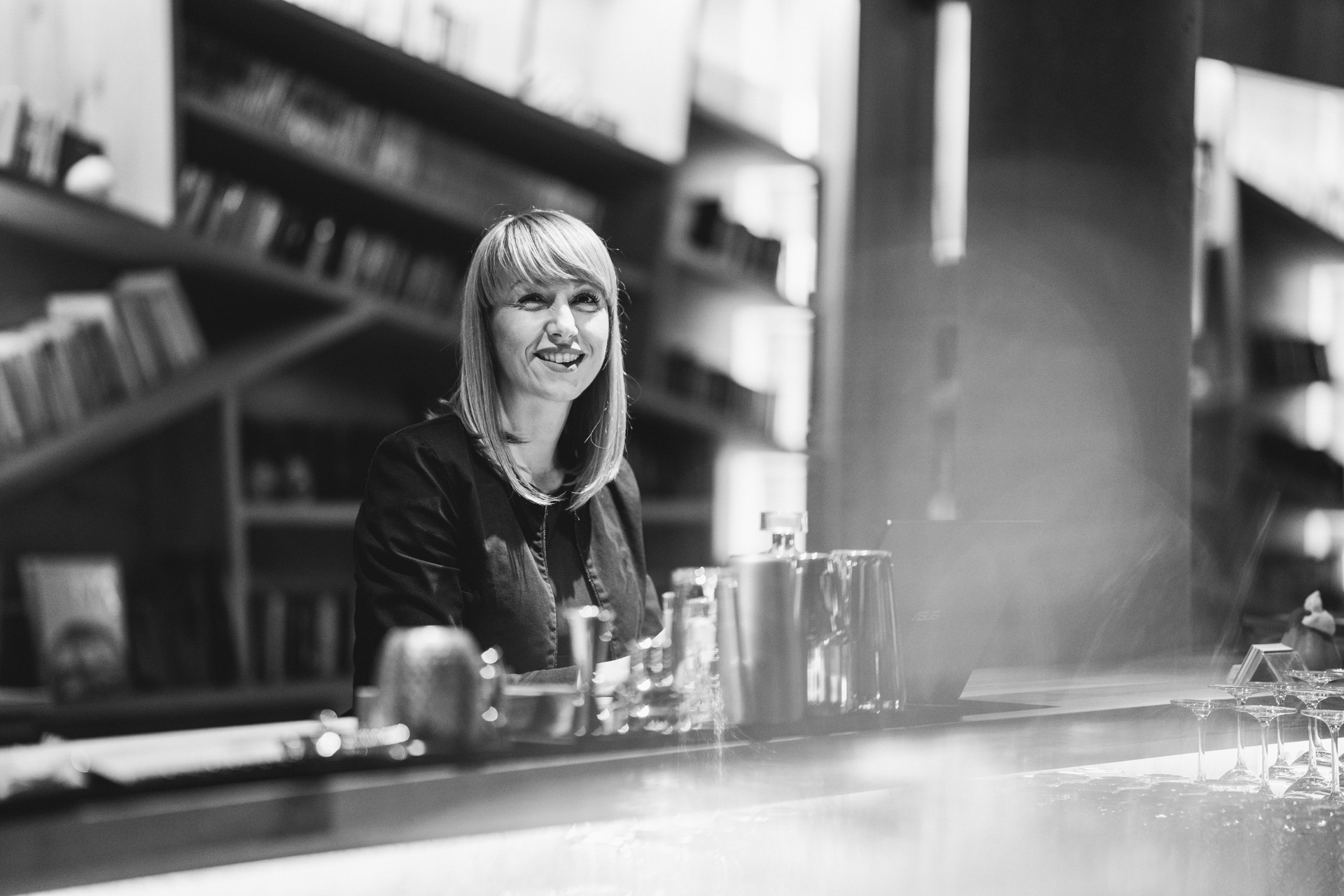 Confident cafe owner standing behind the counter and working on laptop in the evening